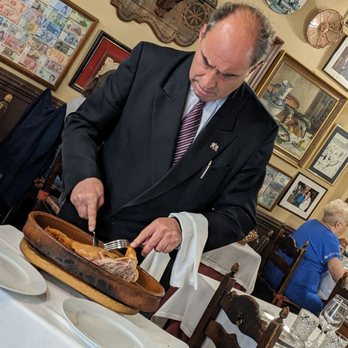 Duque - Waiter cutting our pig in half as table side presentation - Tapas Bars Near Me - Segovia, SG