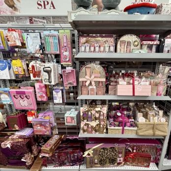 Burlington - Beauty products - Retail store shelves contain an assortment of beauty products, gift sets, and accessories, predominantly in pink packaging. The items include skincare, cosmetics, and gift boxes arranged on metal shelving units. The setting appears to be part of a larger store, with additional products visible in the background, indicating a section dedicated to beauty and personal care items. - Women's Clothing Near Me - Monaca, Pennsylvania