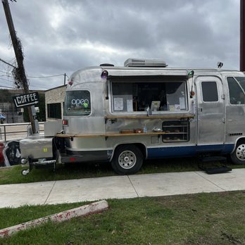 Ufo Coffee - A retro aluminum Airstream trailer serves as a coffee stand, with a window for orders and a small counter outside, situated on a sidewalk. - Coffee & Tea Near Me - Austin, Texas