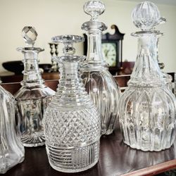 Ardent Estate Sales & Services - Assortment of Antique and Vintage Decanters with Grandfather Clock in Background