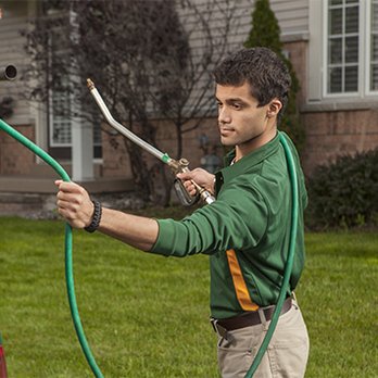 Weed Man - a man using a hose to spray a lawn - Lawn Services Near Me Weed Man - a man using a hose to spray a lawn - Lawn Services Near Me