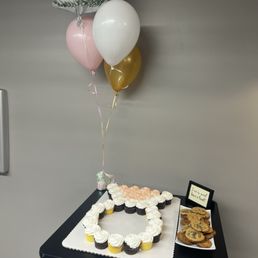 a table with cupcakes and balloons