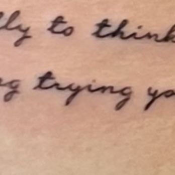 Kunce Tattoo - Trying instead of tying - A tattoo with cursive black ink is visible on skin, showing part of a phrase or sentence. - Tattoo Near Me - Chicago, Illinois