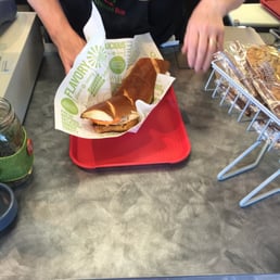 a person preparing a hot dog in a bun a person preparing a hot dog in a bun