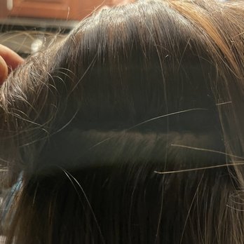 J Salon - Raelyn's work!!! Look how professional this looks! I'm no longer in pain from the beads and I don't feel my hair pulling. - Close-up of a wig or hairpiece with dark roots and lighter brown strands, held by a person's hand. - Hair Salons Near Me - Parker, Colorado