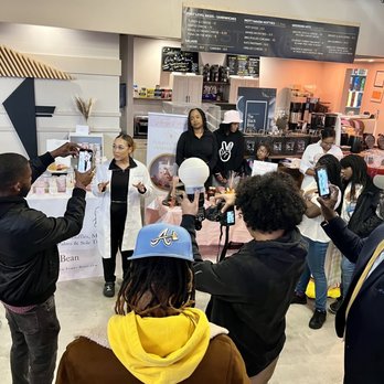 First Level Cafe - a group of people holding up signs - Coffee & Tea Near Me - Bronx, New York