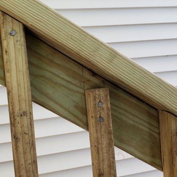 Avatar Construction - oops.  Notice the deck was constructed with nails instead of screws - A wooden staircase with visible nails is shown against a white siding exterior wall, highlighting construction details. - General Contractors Near Me - Watertown, Massachusetts