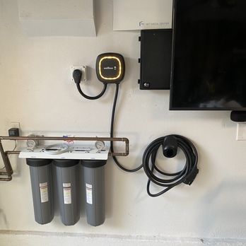 Tingler Electric - 220/240 outlet from Tingler Electric. Came the next day for install. - The image shows an electric vehicle charging station with three filters, a wall-mounted monitor, and a black cable coiled on the wall, installed on a white wall. - Electricians Near Me