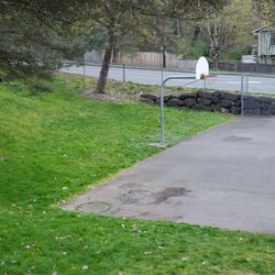 The grassy area behind the basketball court was sloped upwards, nice to not lose a basketball or have it roll too far away from the court