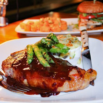 Courier Market Bar Kitchen - The Dry Aged Steak & Potatoes is a bone-in strip topped with bordelaise and a side of potatoes topped with blue cheese and asparagus. - New American Near Me - Denver, Colorado