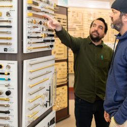 National Builders Hardware - NBH decorative hardware showroom. Sales representative and client selecting cabinet knobs and pulls.