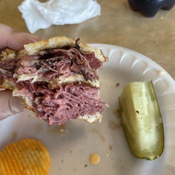 Old World Deli - a hand holding a half eaten sandwich - Delis Near Me - Brunswick, Ohio
