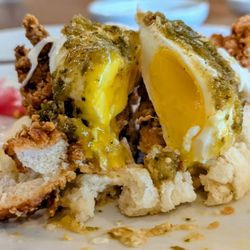 Crispy Chicken Benedict on a biscuit with an egg cut open and Green Chili Sauce