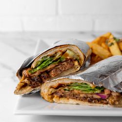 Azara Kitchen - Tender steak slices on a toasted baguette with caramelized onions, arugula, and tangy aioli. Served with crispy fries, it's a bold,