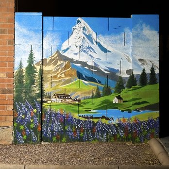 Amer Mural Art - Swiss landscape of the Matterhorn Mountain with Lupine in the foreground, a mountain lake and lodge on a cinderblock wall in Phoenix - Commissioned Artists Near Me - Phoenix, Arizona