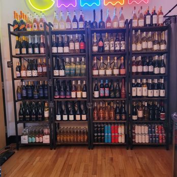 Generation NA - I mean c'mon...Pac-Man and ghosts, yes please - Display of wine and spirit bottles on black shelving units in a beverage shop, with neon Pac-Man and ghost signs above. - Beer, Wine & Spirits Near Me - Lafayette, Indiana