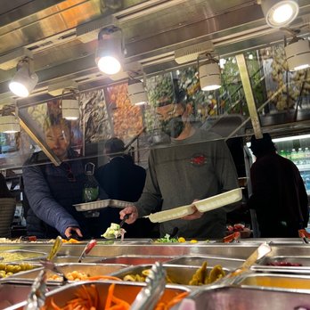 Cafe Manhattan - a man serving food at a buffet - Delis Near Me - New York, New York