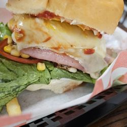 The Monster Den - The X-tudo, a huge burger wrapped in ham, cheese, bacon, topped with corn ketchup lettuce tomatoes mustard. Perfectly cooked fries