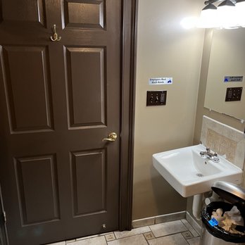 Village Square - a bathroom with a sink and a trash can - American Near Me - Winchester, Virginia