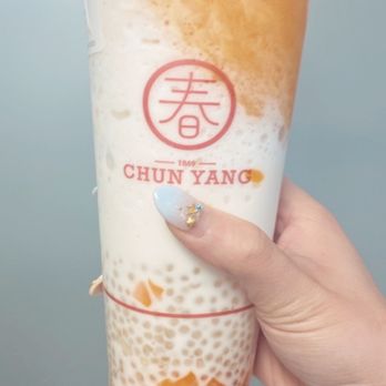 Chun Yang Tea - Mango Coconut Sago; IG: susanlamx - A person holds a Chun Yang bubble tea with tapioca pearls and mango topping, featuring the brand's logo and a red seal. - Bubble Tea Near Me - Brooklyn, New York