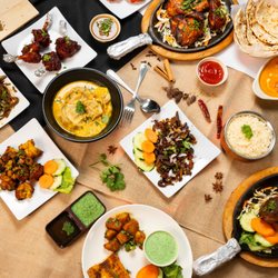 Bhetghat - A colorful spread of authentic Nepali and Indian dishes featuring juicy grilled meats, steaming dumplings in sauce, crispy fried snacks.