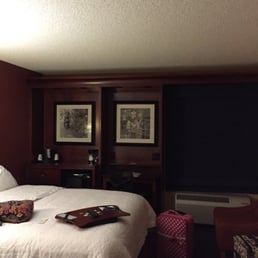 View of the desk, microwave, fridge and bed, from the tiled "hall".