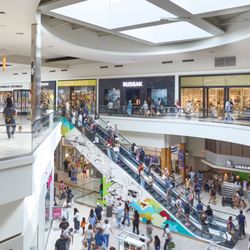 Fashion Outlets of Chicago - Shoppers use escalators between two levels near Burberry and Jimmy Choo.