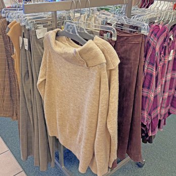 Cato - Some of their clothes - A clothing rack in a retail store displays sweaters, pants, and shirts in various colors and patterns, including plaid and solid tones. - Accessories Near Me - Bedford, Texas