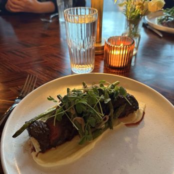 The Maker Restaurant - A dish featuring a piece of cooked meat topped with microgreens, served with mashed potatoes, on a white plate at a restaurant. - Cocktail Bars Near Me - Hudson, New York