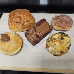 Clockwise: pain au chocolat, flourless brownie, cinnamon sugar beignet, blueberry scone, Nutella beignet Clockwise: pain au chocolat, flourless brownie, cinnamon sugar beignet, blueberry scone, Nutella beignet