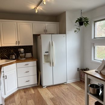 Empire Today - a kitchen with white cabinets and wood floors - Carpet Installation Near Me
