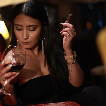Cheroot Cigar Lounge - a woman with a cigar and a glass of wine - Lounges Near Me - Modesto, California