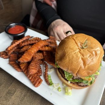 Modern Plate - american burger - A cheeseburger with lettuce and beef patty on a bun, accompanied by crinkle-cut fries and a small container of ketchup. - Cocktail Bars Near Me - Elmhurst, Illinois