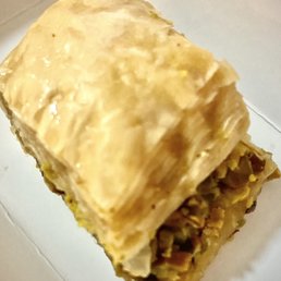 Baklava - A close-up of a rectangular piece of baklava showing its flaky, golden-brown layers and chopped nut filling.