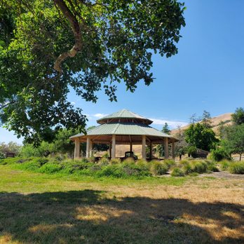 Sandy Wool Lake - Gazebo - A circular gazebo with a metal roof is located in a grassy park area, surrounded by trees and hills under a clear blue sky. - Lakes Near Me - Milpitas, California