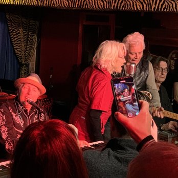 Hernando’s Hide-A-Way - shows a group of people taking pictures of a musician - New American Near Me - Memphis, Tennessee