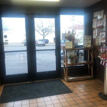 Randys Restaurant - Inside a business, glass doors lead outside, with a welcome sign and flower arrangement on a wooden shelf near the entrance. - American Near Me - Red Wing, Minnesota