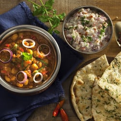 Swadisht - Punjabi Chole. Grão de bico cozido ao molho curry, acompanhado por Pudina Naan, pão indiano com hortelã, assado na hora no forno tandoor.