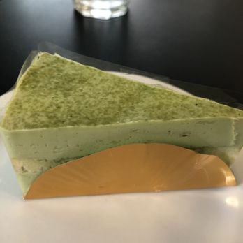 Hiroki - Macha cheesecake.  The gold circle wrapper on the bottom and the edges are protected by the clear plastic around the perimeter. - Bakeries Near Me - Seattle, Washington