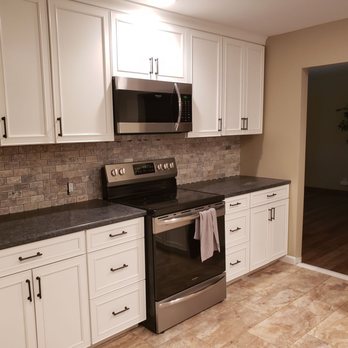 Platinum Connections - a kitchen with white cabinets and black countertops - General Contractors Near Me Platinum Connections - a kitchen with white cabinets and black countertops - General Contractors Near Me