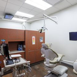 Guildford Town Centre Dental - Bright dental treatment room with a patient chair, overhead light and digital monitor at Guildford Town Centre Dental