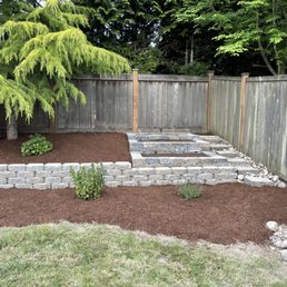 Retaining wall and tiered garden beds, with stairs on side. Added water spigot at the top. Added bark for a nice finishing touch!