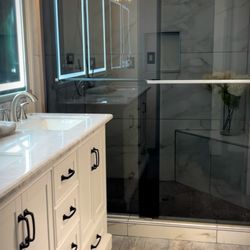 Alcantar Construction - This bathroom renovation consisted installing new tile flooring, vanity mirror with lights, and new shower doors.