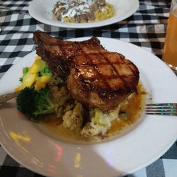Double Stuffed Pork Chop on Signature Horseradish Mashed Potatoes and Beef Stroganoff in the background.