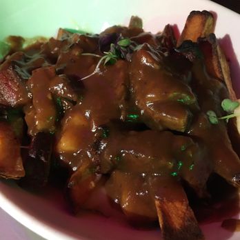 Slainte of Peekskill - A bowl of fries covered with gravy and garnished with microgreens, served in a restaurant setting. - Irish Pub Near Me - Peekskill, New York
