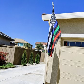 Santo Tomas Landscape - a flag on a pole in front of a garage - Landscaping Near Me