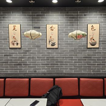 Master Noodle - Interior of a restaurant with a gray brick wall, Asian-style hanging lanterns, and framed artwork depicting traditional scenes. - Chinese Near Me - Bloomington, Minnesota