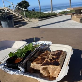 Naked Cafe - Crispy burritos with side of beans and potatoes hiding under the cilantro - Breakfast & Brunch Near Me - Solana Beach, California Naked Cafe - Crispy burritos with side of beans and potatoes hiding under the cilantro - Breakfast & Brunch Near Me - Solana Beach, California