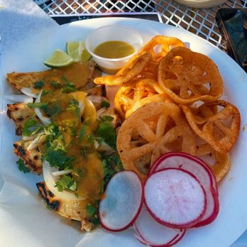 Gobble This - A food plate featuring pupusas topped with cilantro, onion, and sauce, served with onion rings, radish slices, and a small container of green sauce. - Salvadoran Near Me - Albuquerque, New Mexico