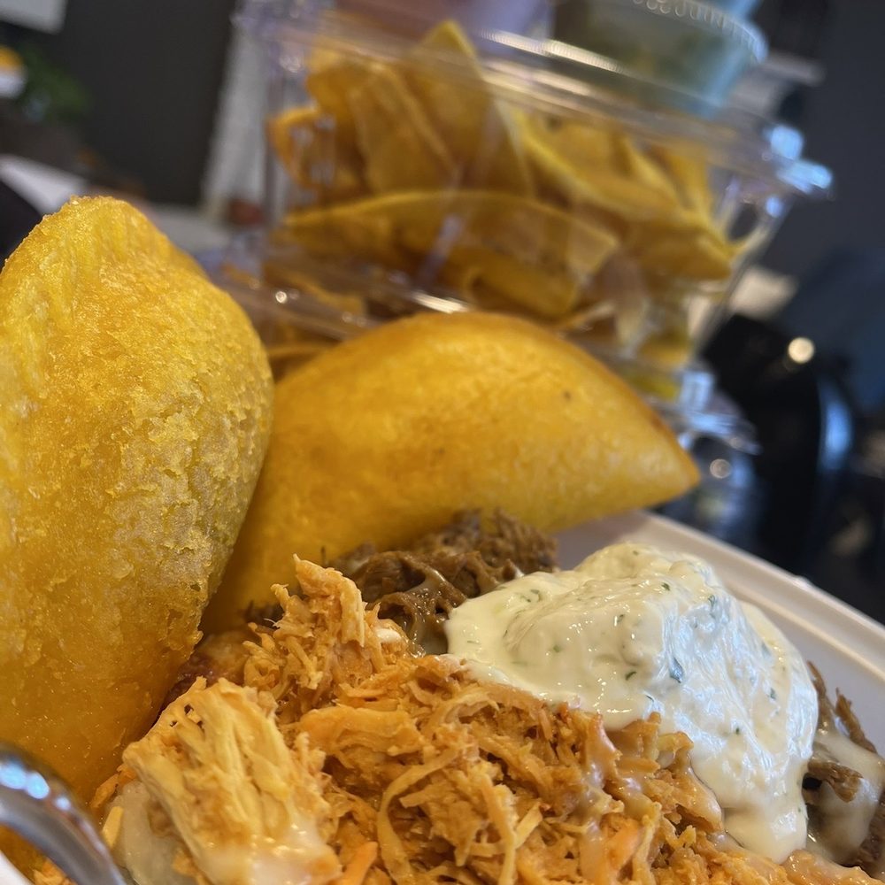 Stuffed arepa, beef empanada & chicken empanada- background is plantain chips with verde & Roja.